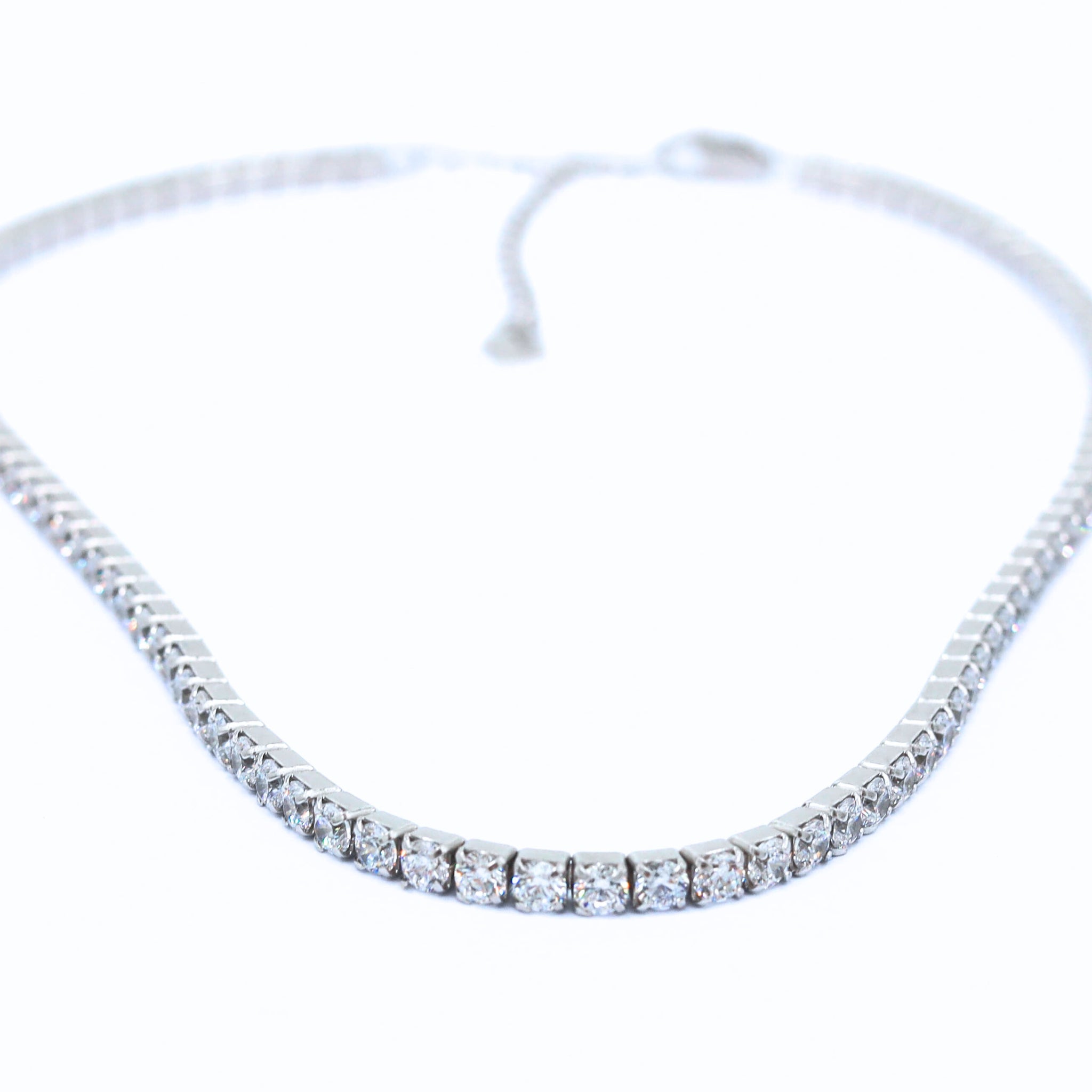Silver Tennis Necklace featuring a delicate line of sparkling cubic zirconia stones set in a sleek, polished sterling silver chain, perfect for adding elegance to any outfit. Rhodium plated