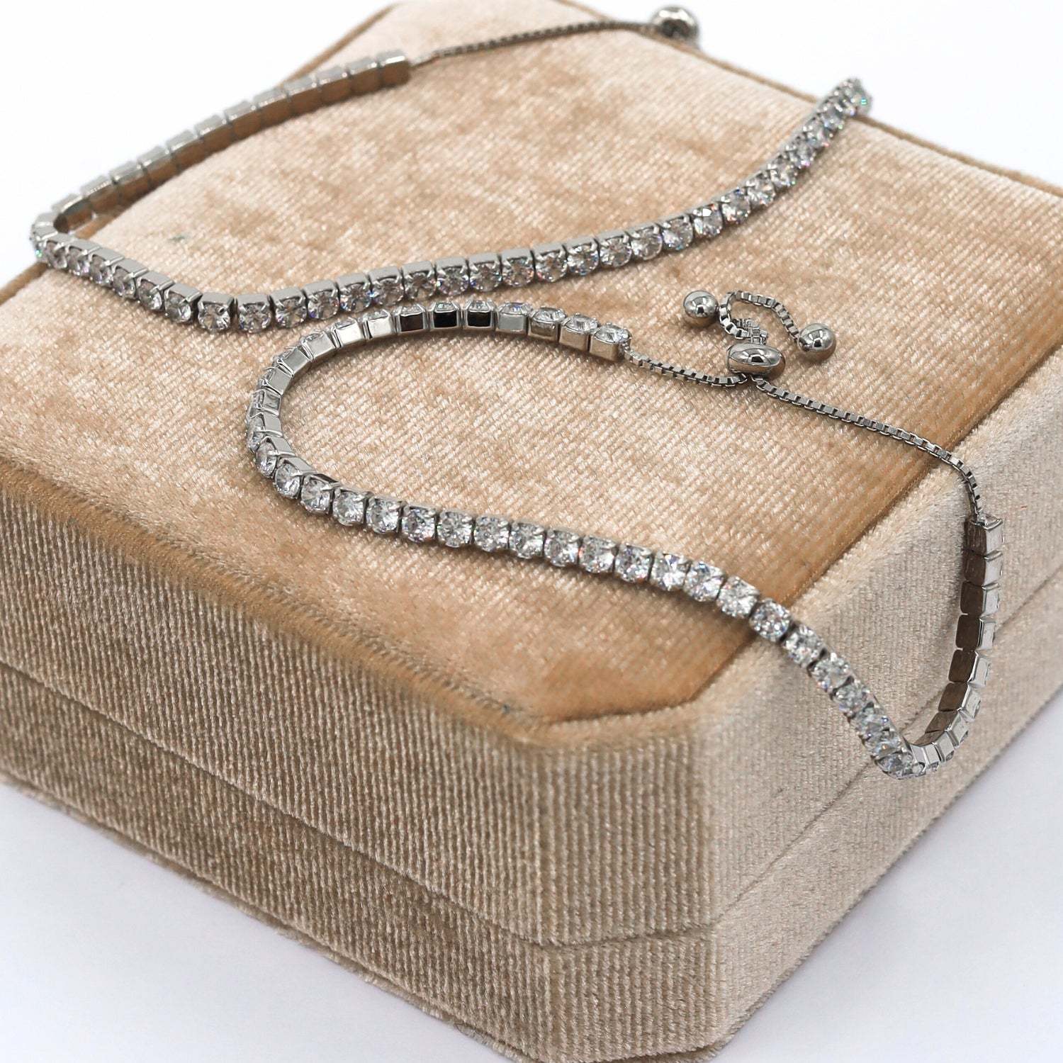 Tennis Bracelet Bijou in Silver, featuring round sparkling cubic zirconia stones set in a high-quality sterling silver band, offering a chic and elegant design for a refined look. Rhodium plated. The two bracelets are laid on top of our luxurious velvet boxes that come with all the jewelry.
