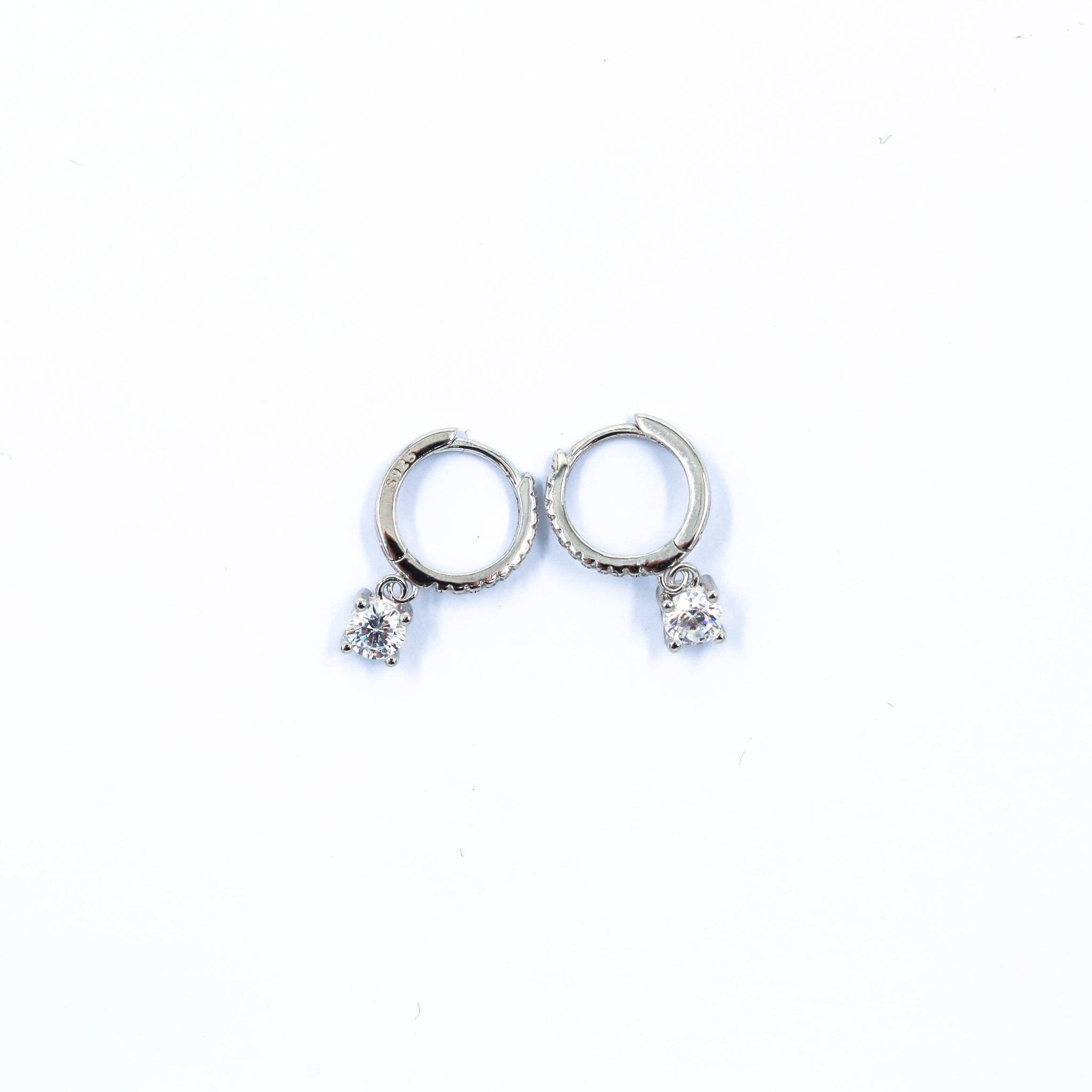 Hoop Earrings in Silver, crafted from 925 sterling silver, featuring a sleek hoop design with sparkling round cubic zirconia accents for a classic, elegant look. Rhodium plated