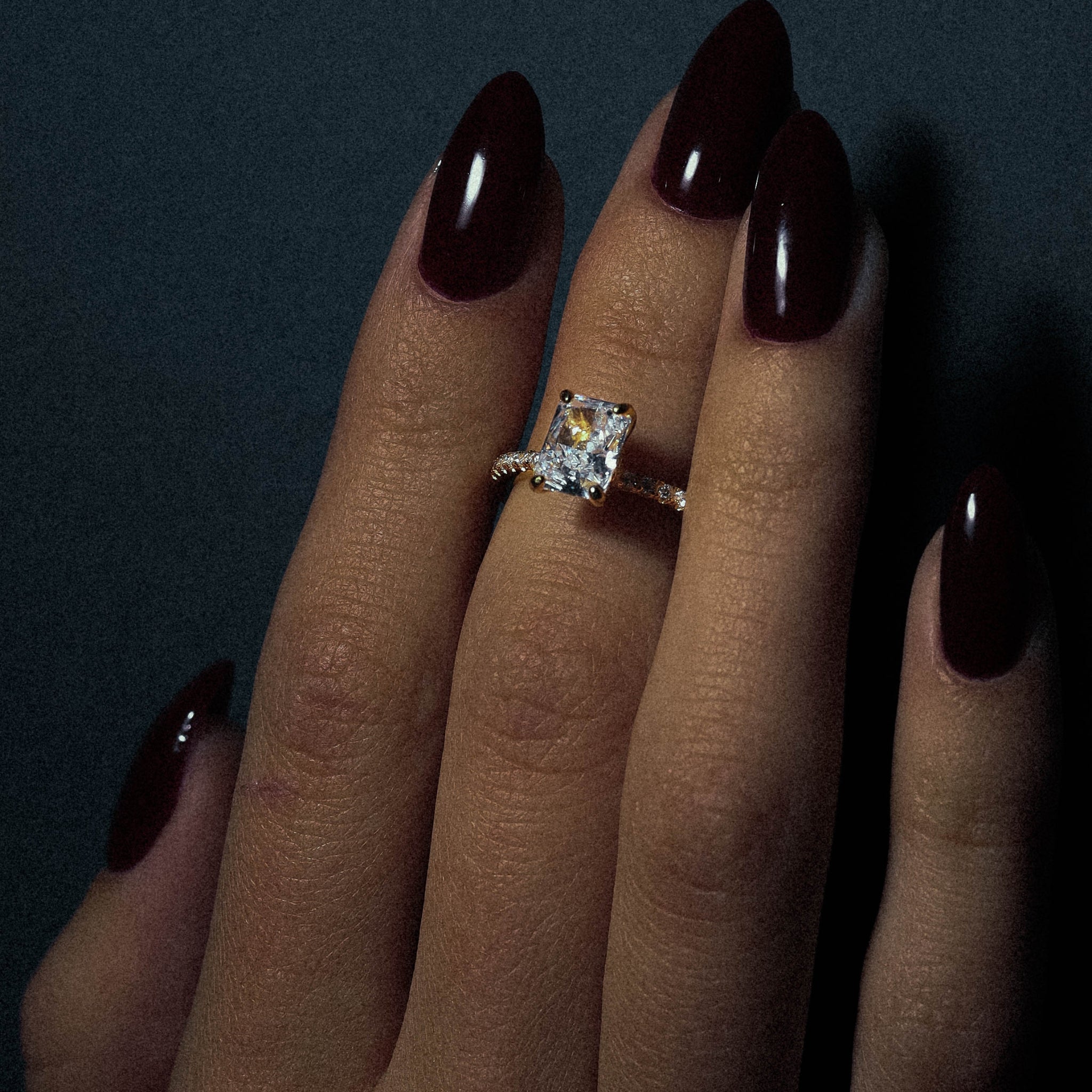 Kapi Rectangular Cut Ring in Gold worn on finger, highlighting the sleek gold-plated finish and eye-catching rectangular center stone with pave cubic zirconia for a refined look.