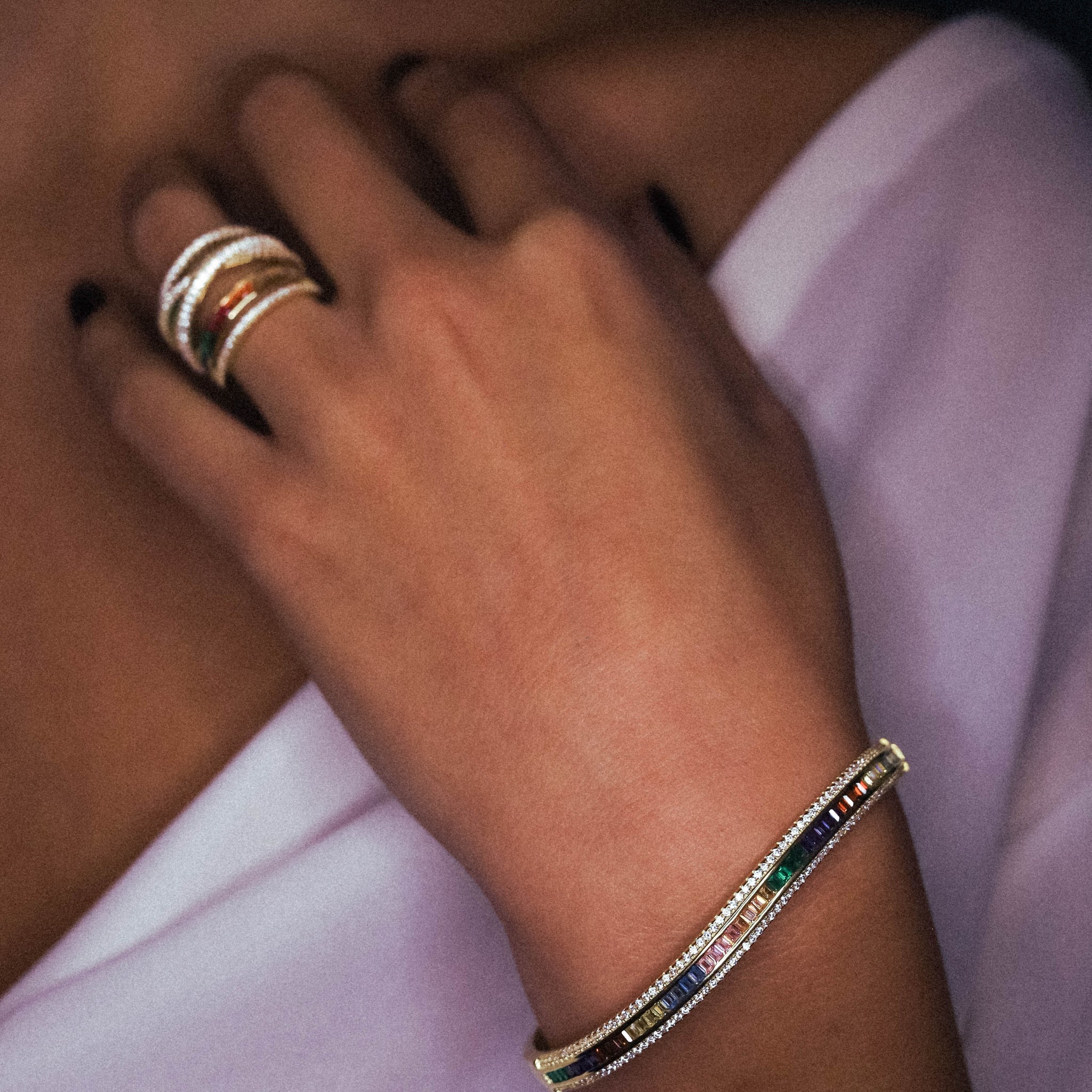 Close-up of the Chroma Bangle Bracelet showcasing its gold-plated finish and colorful cubic zirconia stones in a sophisticated prong setting, combined with the chroma ring in gold. 